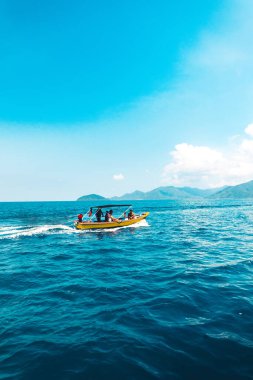 Adada temiz su, açık mavi deniz ve ahşap tekne.
