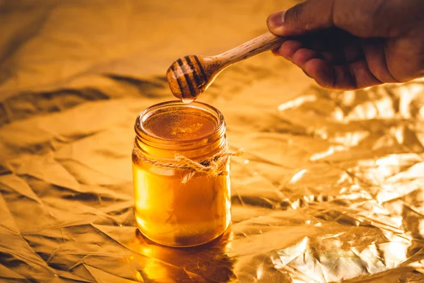 Golden honey in a glass bottle and golden background,Honey scoop