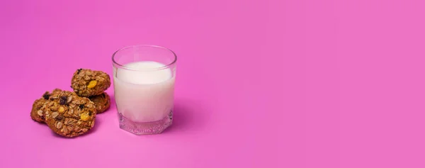 Cereal cookies and milk in a glass on a pink background