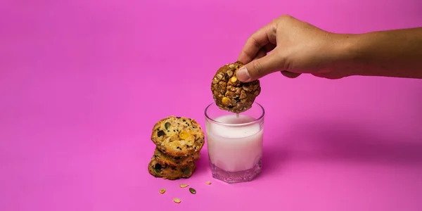 Cereal cookies and milk in a glass on a pink background