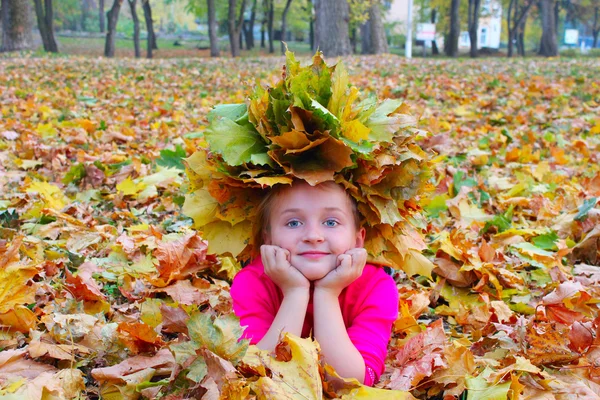 Fille avec une couronne de feuilles jaunes sourit — Photo