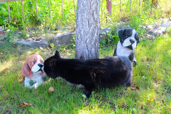 Черный кот пахнет искусственными керамическими собаками — стоковое фото