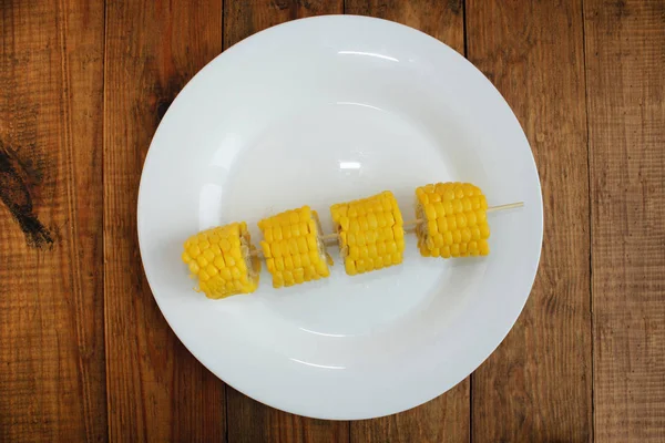 Morceaux coupés de maïs bouilli sur l'assiette sur le fond en bois — Photo