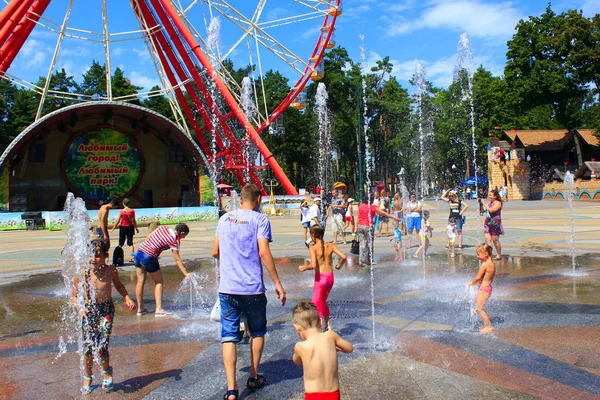 Дети играют на детской площадке с фонтанами в жаркое лето в Харькове — стоковое фото