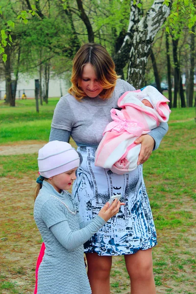 Šťastný matka s dcerou starší prohlédnout fotografie novorozence — Stock fotografie