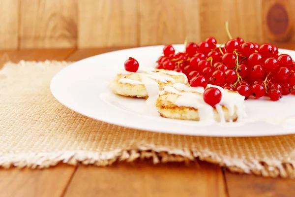 Cheese cakes and berries of fresh red currant on the plate — Stock Photo, Image