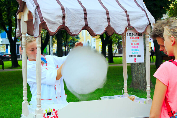 Девушка продает сладкую вату в городском парке
