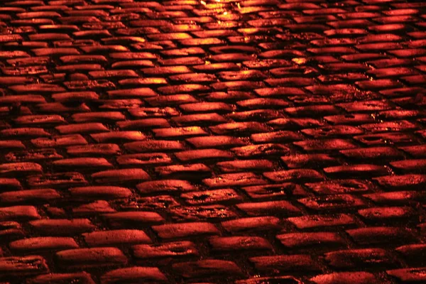 Road pavement gjorda av sten block i rött ljus — Stockfoto