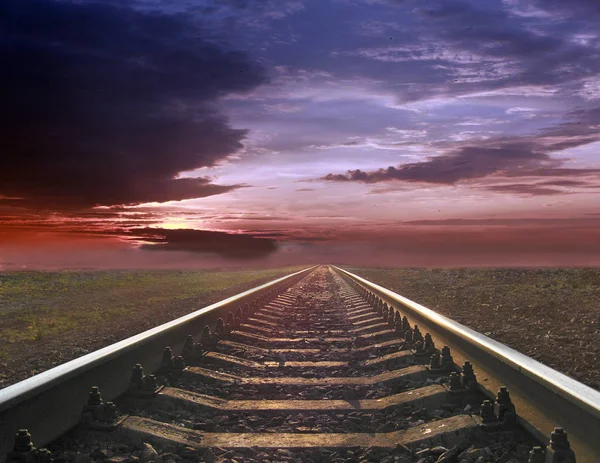 Paysage sombre avec des rails s'éloignant dans le coucher du soleil lointain — Photo