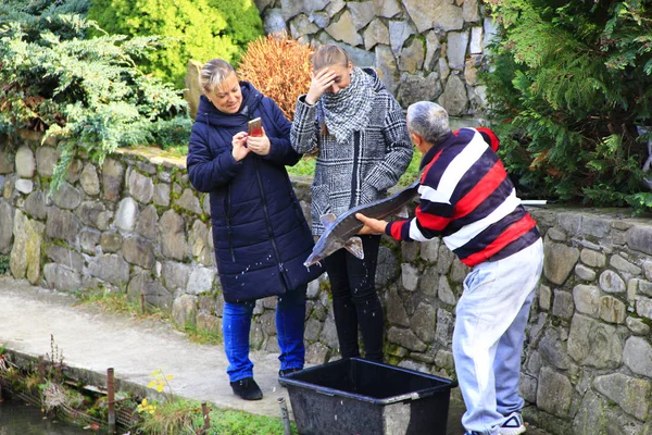 Un uomo mostra uno sterlet catturato alle donne che lo fotografano — Foto Stock