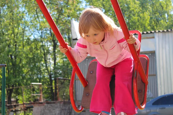 ブランコに乗っている少女を果たしています。良い年の幼年期 — ストック写真