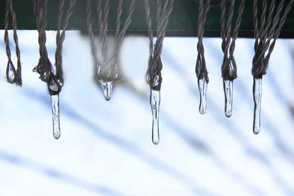 Ijspegels hangen af van koorden buiten. Bevroren water — Stockfoto