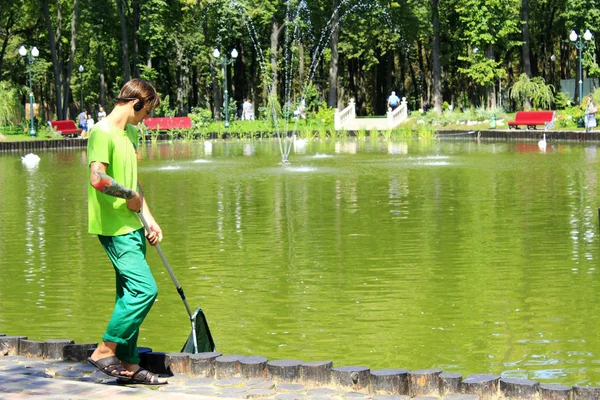 Young man keeps cleanliness in the city pond — Stock Photo, Image