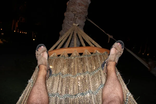 Ben turist vilar i hängmatta på natten. Foten av man rullande i hängmatta — Stockfoto