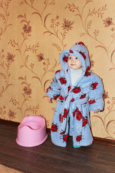 Funny baby in bathrobe near plastic potty — Stock Photo, Image