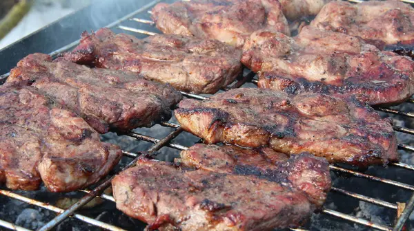 Trozos de carne con cebolla se cocinan en la barbacoa. Cocinar carne durante el picnic — Foto de Stock