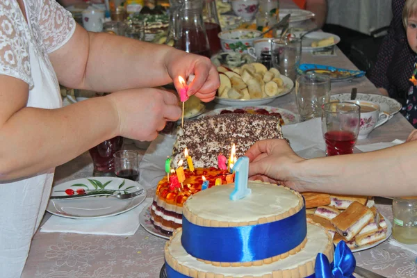Matka dekorowanie świąteczne ciasto ze świecą na urodziny syna — Zdjęcie stockowe