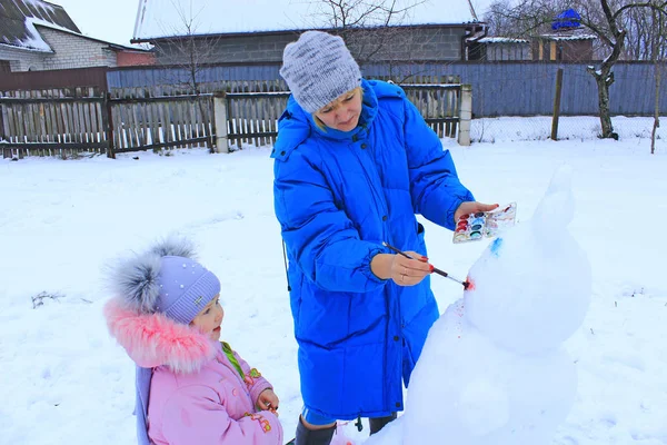 Mother painting snowman. Enjoying winter holidays. Winter family vacations — Stock Photo, Image