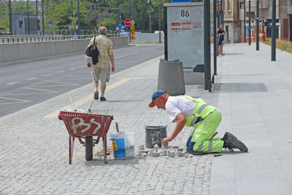 Uomo posa marciapiede. Lastre per pavimentazione operaia in città — Foto Stock