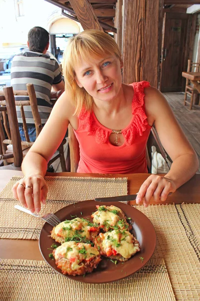 Belle femme mangeant un plat charnu au restaurant et souriant — Photo