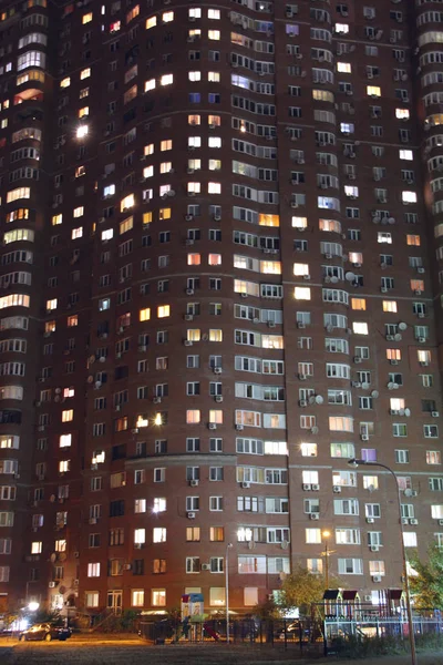 Panorama noturno da luz nas janelas do edifício de vários andares. Vida em cidade grande — Fotografia de Stock