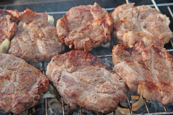 Steak grilling on fire. Process of cooking meat. Steak on barbecue. Pieces of grilled meat on grill. Cooking of pork. Barbecue lunch outdoors. Process of cooking meaty food on fire