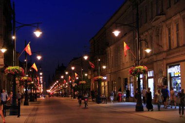 Lodz / Polonya. 18 Temmuz 2019: Lodz Piotrkowska 'nın merkez caddesi. Geceleri Polonya 'nın ana turistik caddesi Lodz Piotrkowska. Piotrkowska caddesindeki Lodz 'da insanlar dinleniyor. Kafede insanlar rahatlar.