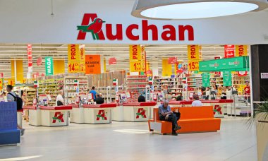Lodz / Polonya. 18 Temmuz 2019: Auchan mağazalarında müşterilerle birlikte mal raflarının ve nakit kasalarının görünümü. Auchan hipermarketindeki kasiyer bölgesi. Auchan mağazasında çeşitli ürünler satılıyor..