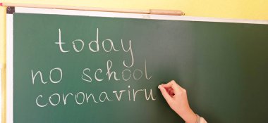 Kızın eli bugün karatahtaya Coronavirus diye bir şey yazmıyor. Sınıfta Coronavirus uyarı işareti var. Koronavirüs salgınının okul iptali. Okulun iptali. Salgın geliyor.