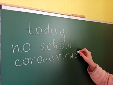 Kızın eli bugün karatahtaya Coronavirus diye bir şey yazmıyor. Sınıfta Coronavirus uyarı işareti var. Koronavirüs salgınının okul iptali. Okulun iptali. Salgın geliyor.
