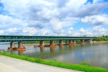Varşova 'da Wisla üzerinde uzun bir köprü. Varşova 'daki Wisla Nehri üzerindeki modern köprü. Nehir bulutları ve köprü manzarası. Wisla Nehri ve köprüsü kıyısındaki setler.