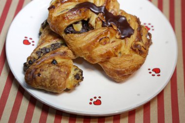 Beyaz plaka üzerinde çikolata ile taze kruvasan.