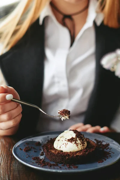 Девушка ест шоколадный десерт коричневый с белым кремом — стоковое фото