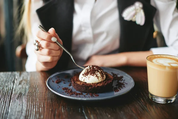 Девушка ест шоколадный десерт коричневый с белым кремом — стоковое фото