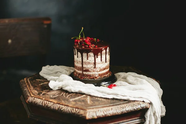 Kue coklat dengan buah merah currant di meja kayu tua — Stok Foto