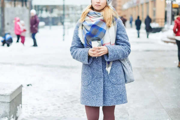 Flicka i grå kappa, mössa och filt halsduk med kopp kaffe på vintern street — Stockfoto