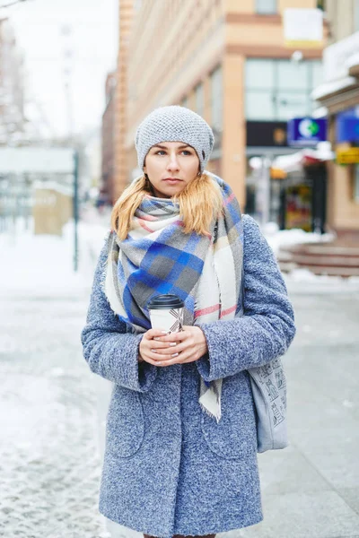 Menina de casaco cinza, chapéu e lenço com xícara de café na rua de inverno — Fotografia de Stock