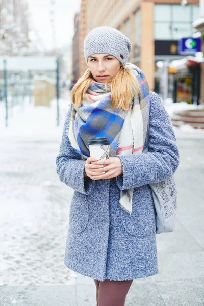 Menina de casaco cinza, chapéu e lenço com xícara de café na rua de inverno — Fotografia de Stock