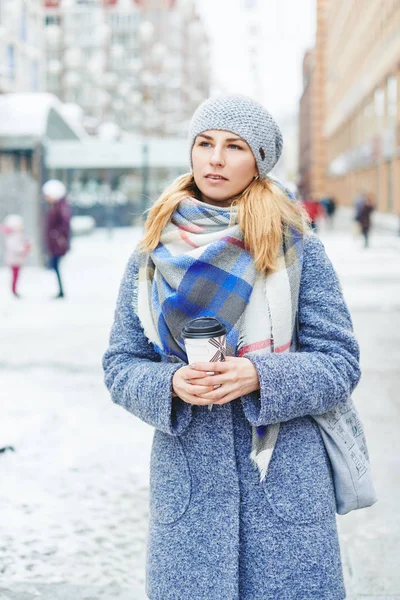 Menina de casaco cinza, chapéu e lenço com xícara de café na rua de inverno — Fotografia de Stock