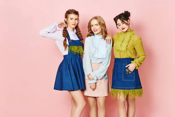 Модна фотографія трьох молодих дівчат, які позують на рожевому фоні в студії — стокове фото