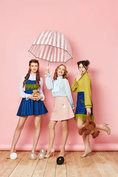 Foto de moda de três jovens posando sobre fundo rosa em estúdio — Fotografia de Stock