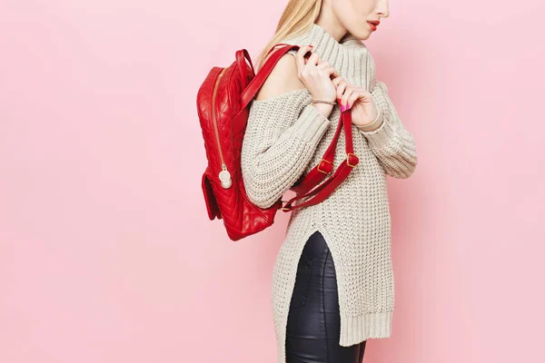 Kadın moda model pembe arka plan stüdyo üzerinde kırmızı sırt çantası ile