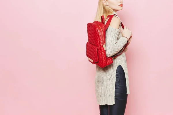 Kadın moda model pembe arka plan stüdyo üzerinde kırmızı sırt çantası ile