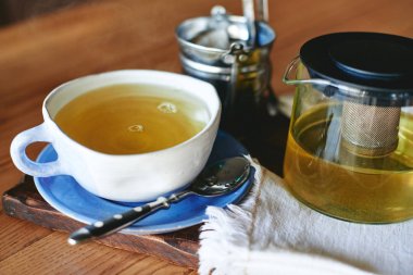 Seramik kupa ve ahşap masa üzerinde yeşil çay çaydanlık