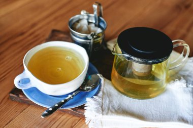 Seramik kupa ve ahşap masa üzerinde yeşil çay çaydanlık