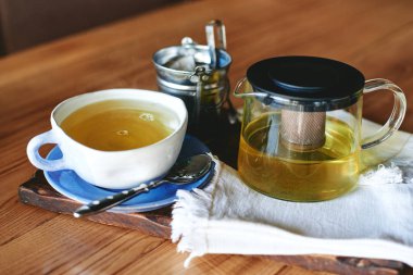 Seramik kupa ve ahşap masa üzerinde yeşil çay çaydanlık