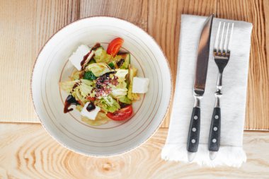 Ahşap masa üzerinde Yunan salatası ile seramik kase