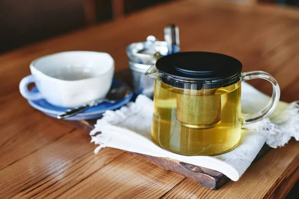 Tazza di ceramica e teiera con tè verde su tavola di legno — Foto Stock