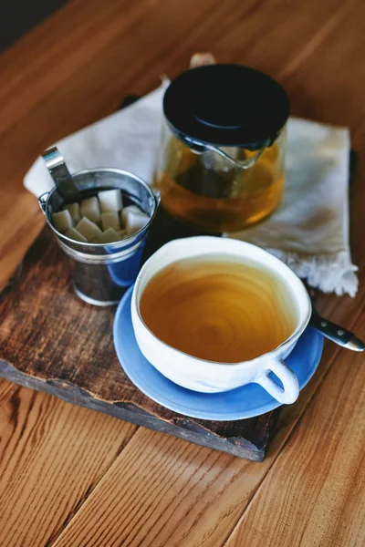 Seramik kupa ve ahşap masa üzerinde yeşil çay çaydanlık