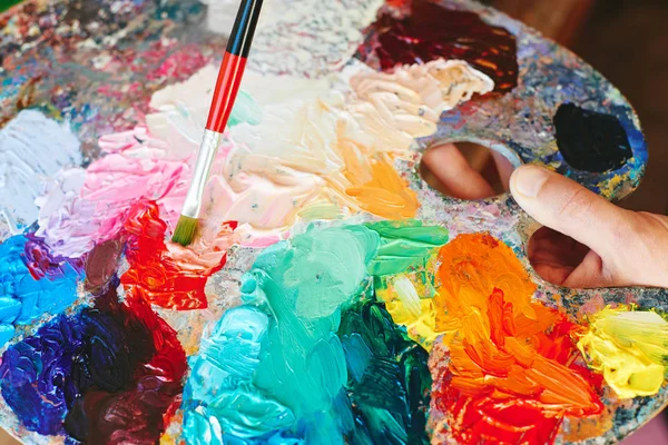 Artista segurando pincel de pintura e paleta de óleo colorido — Fotografia de Stock